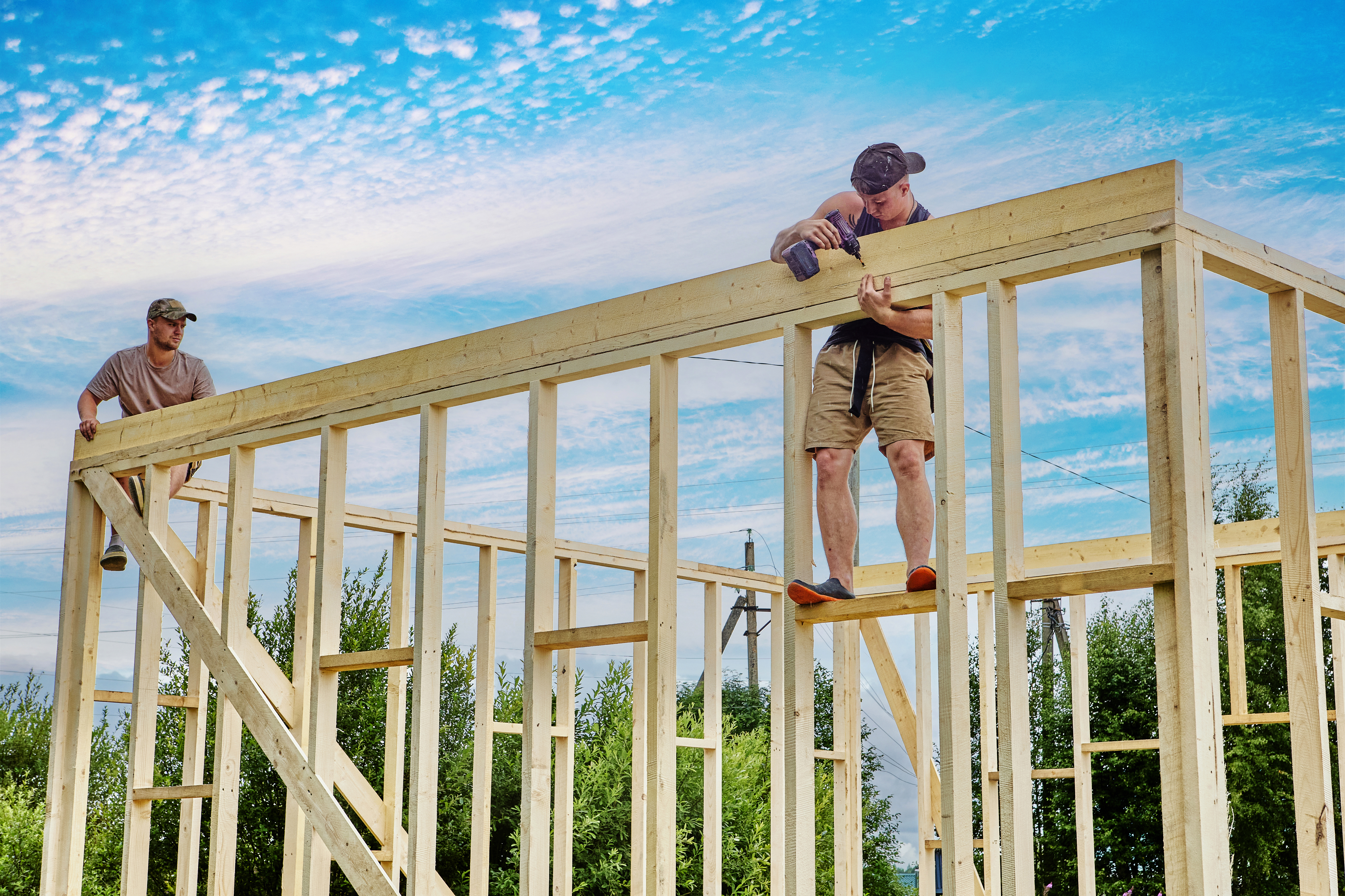 Construction crew builds frame house on foundation made of concrete blocks.